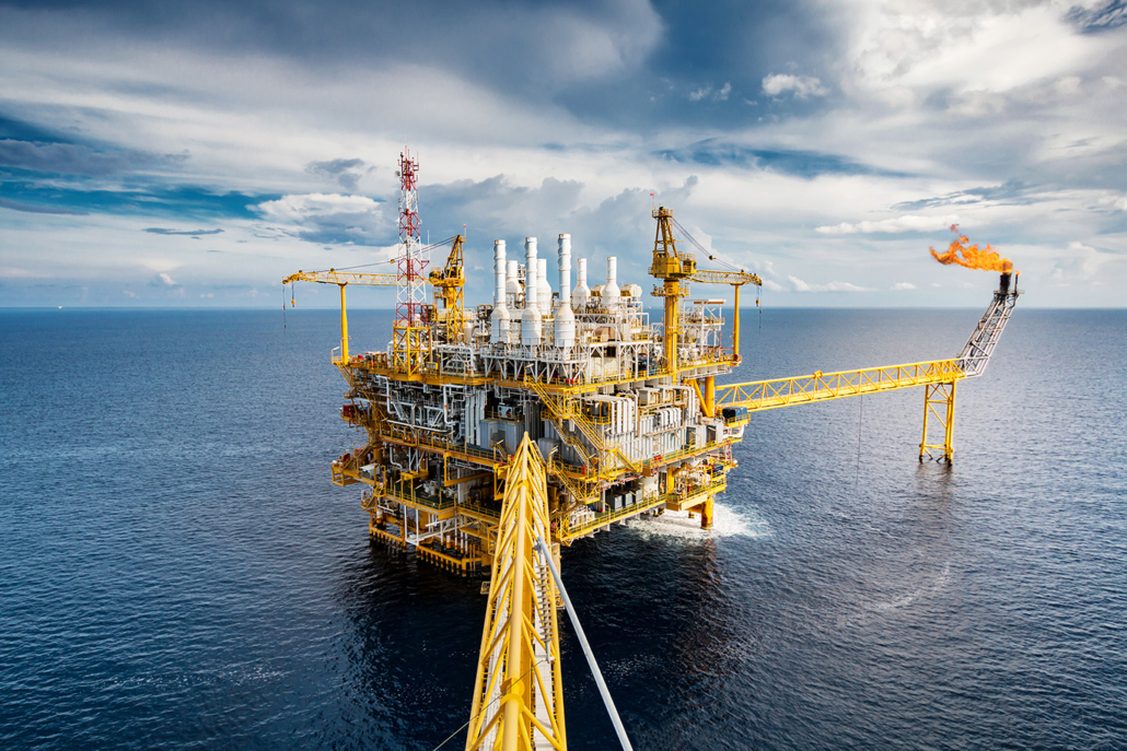 Offshore oil and gas production platform with processing equipment, cranes and a flare stack at sea.