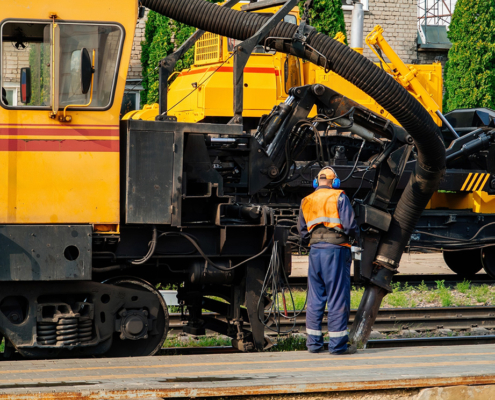 Pneumatic Solutions for Rail and Infrastructure Applications Technician operating railway maintenance equipment beside a specialized rail vehicle.